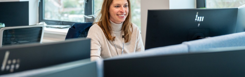 Woman working cheerfully on her desktop at Nimbuscare Head Office