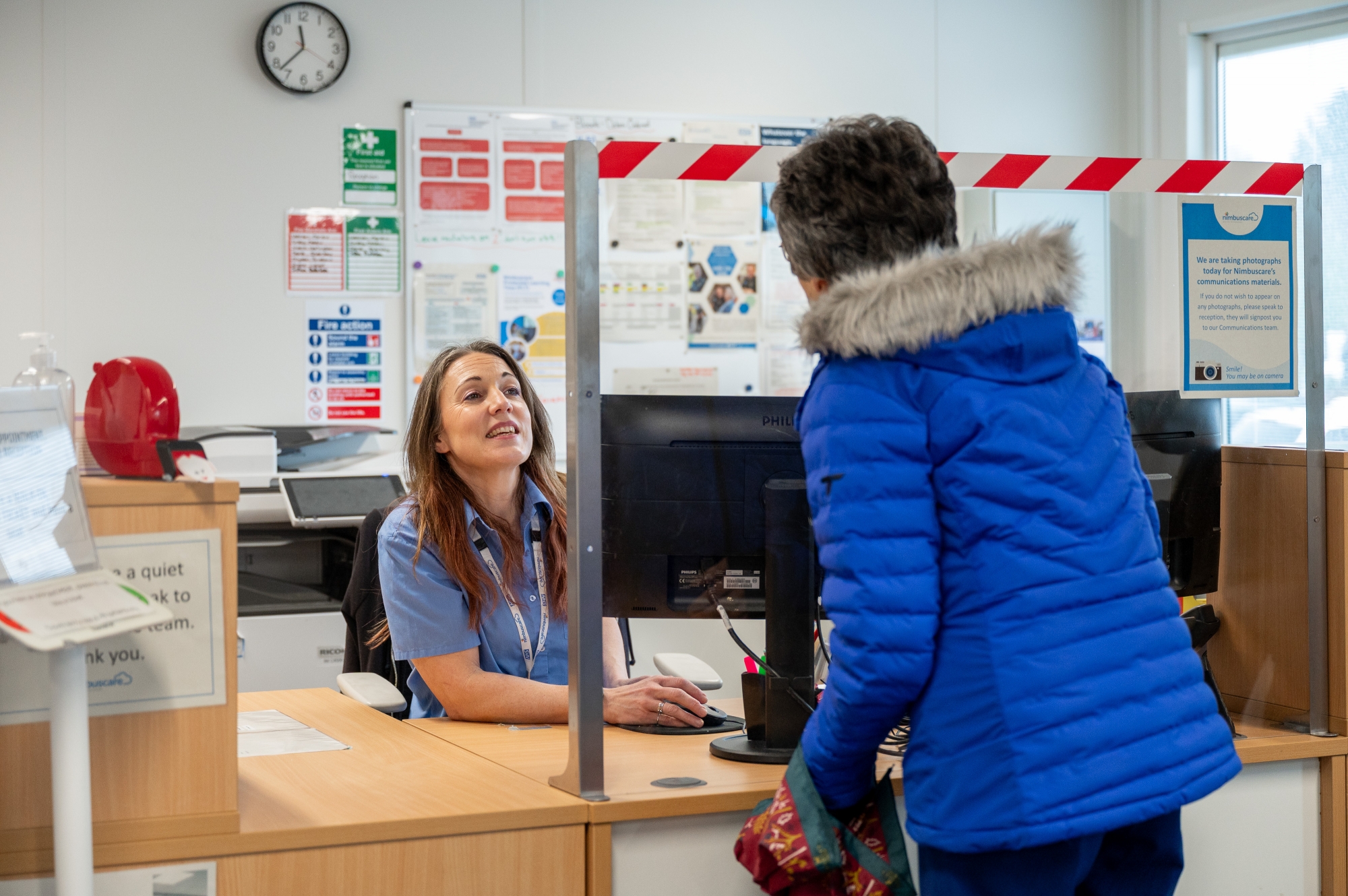 Female patient interacting with receptionist at healthcare centre